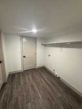 Dedicated laundry area with wood-finish flooring, white walls, and a built-in wire shelf