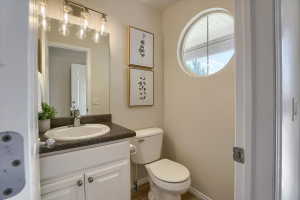 Bathroom featuring a white vanity with built-in sink, dark countertop, and a round window