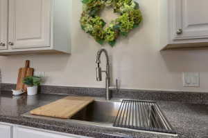 Kitchen sink with a high-arc pull-down faucet, undermount stainless steel sink, and speckled countertop