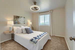 Carpeted bedroom featuring neutral wall tones, a modern ceiling fan with integrated lighting, a window with blinds and drapes, and white baseboards