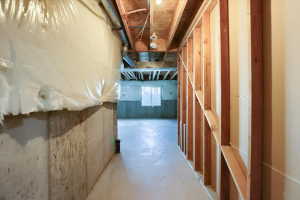 Unfinished lower level featuring exposed wooden studs, concrete walls, and a concrete floor