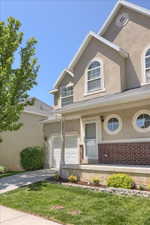 Stucco exterior featuring arched and circular windows, a two-car garage, and a covered porch with brick accents