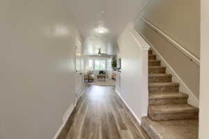 Entryway featuring wood-finish flooring, light neutral paint, a carpeted staircase with white trim, and a white interior door