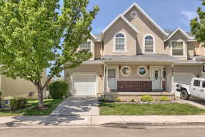 Stucco exterior featuring arched and circular windows, an attached garage, and a covered entry porch with brick detailing