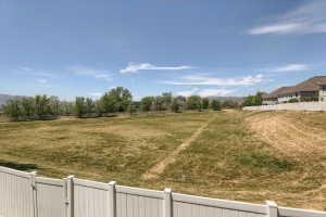 Expansive rear property with a white vinyl privacy fence and a broad grass area