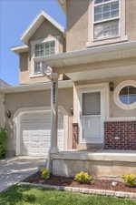 Stucco facade home featuring an attached garage, covered porch entry, and an architectural round window
