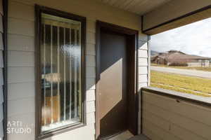 Exterior entry featuring horizontal siding, a solid brown door, and a textured glass sidelight with vertical mullions