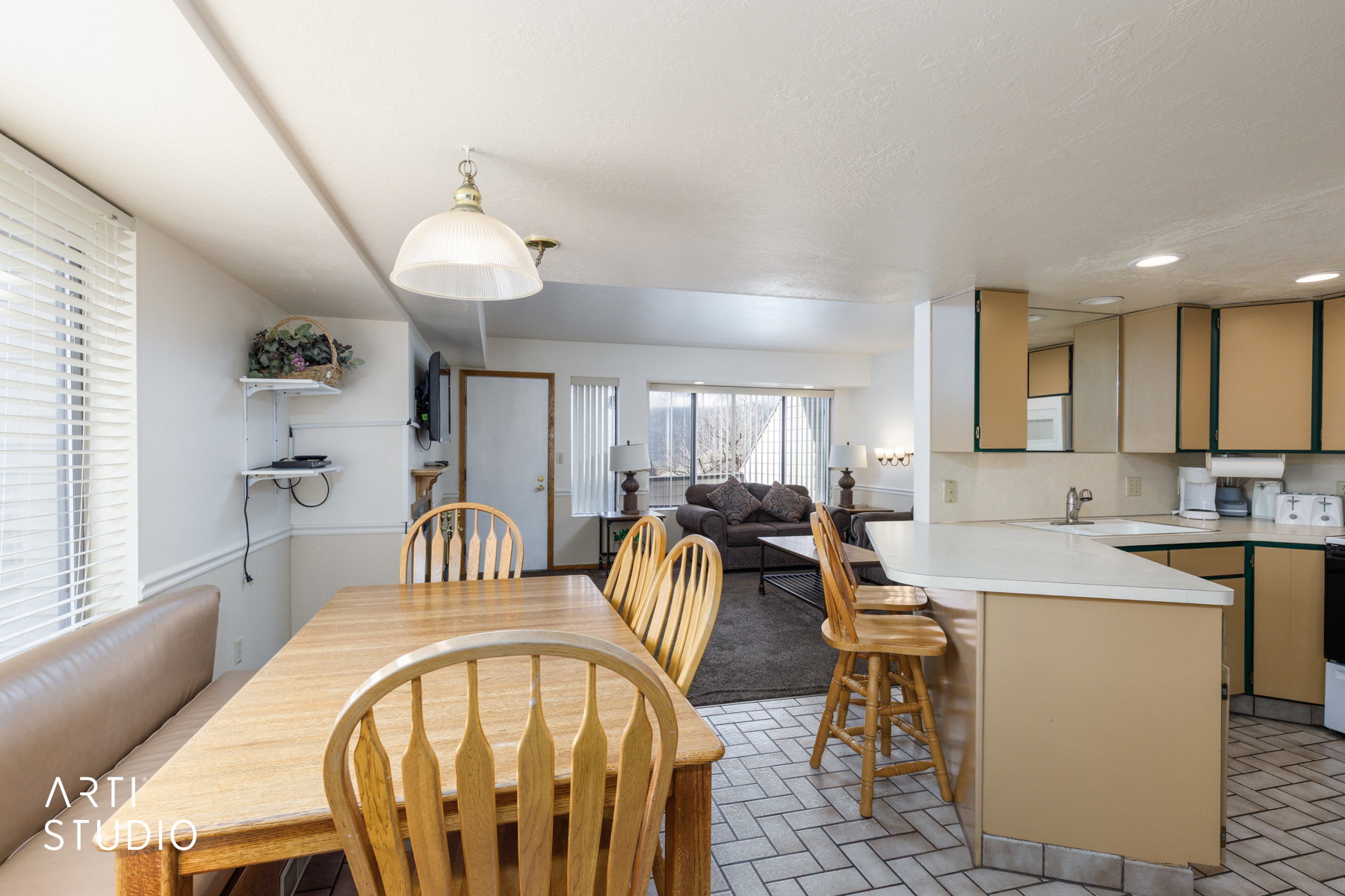 Open-concept living space featuring a kitchen with a peninsula and breakfast bar, white countertops, and a dining area with a built-in bench
