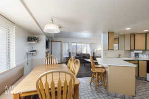 Open-concept living space featuring a kitchen with a peninsula and breakfast bar, white countertops, and a dining area with a built-in bench