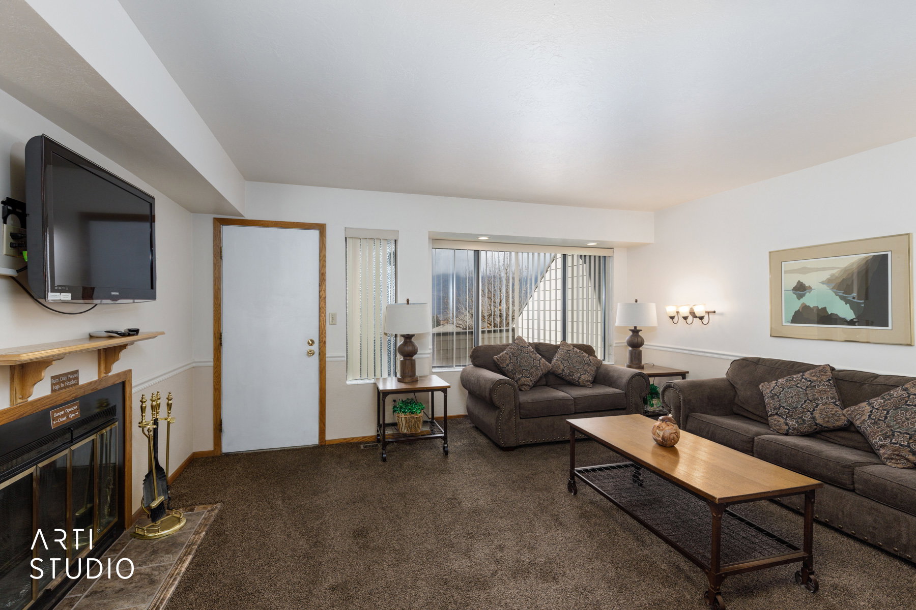 Living area featuring a fireplace with a wood mantle and dark-toned carpet flooring