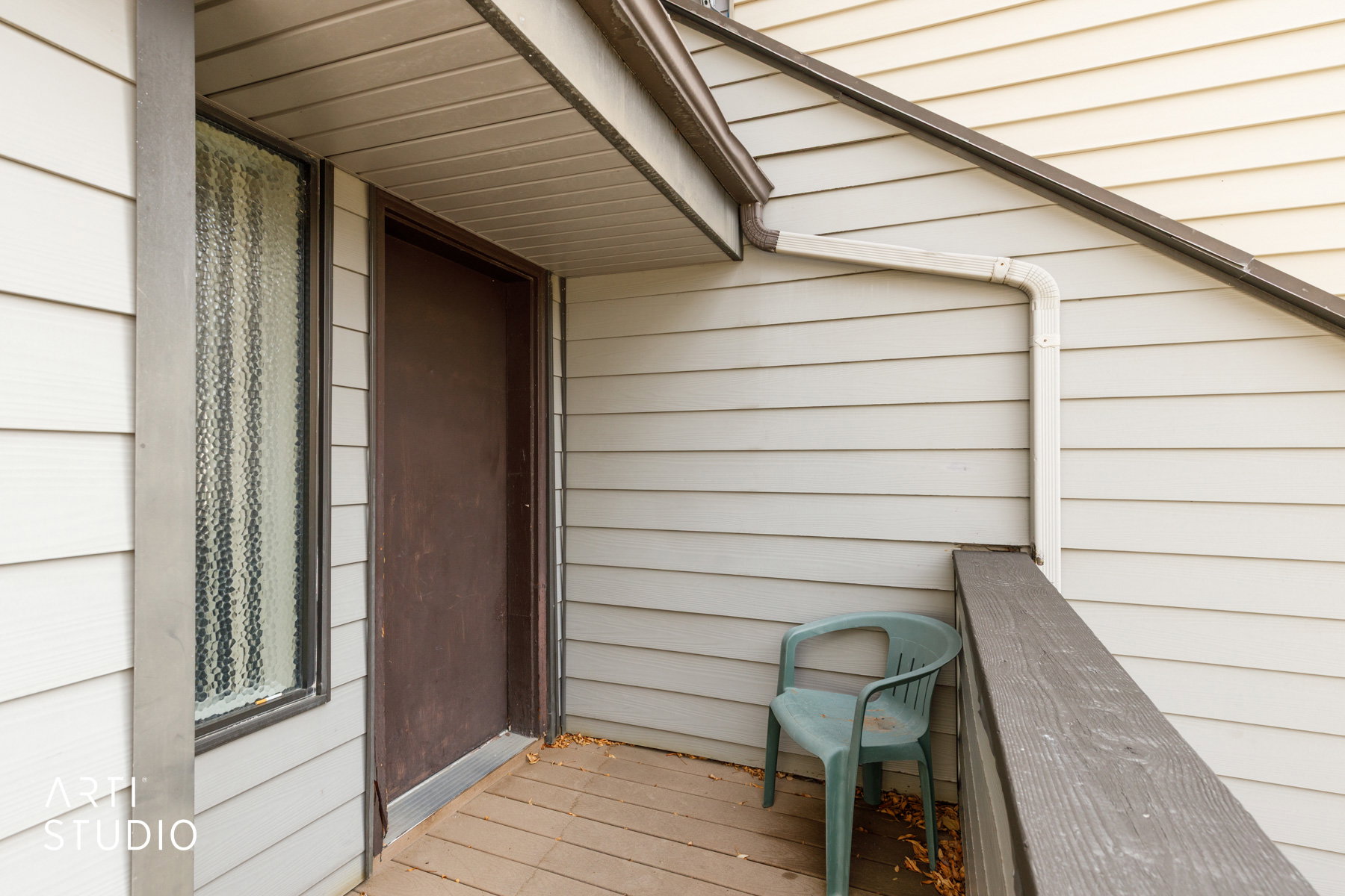 Covered outdoor balcony featuring horizontal siding and a dark paneled entry door