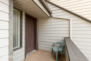 Covered outdoor balcony featuring horizontal siding and a dark paneled entry door
