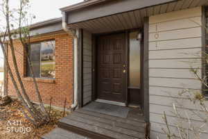 Exterior entryway featuring a paneled door, sidelight, wall-mounted light fixture, and address numbers