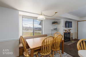 Dining area featuring a built-in banquette, a large window with blinds, a fireplace with a mantel, and mixed flooring of tile and carpet