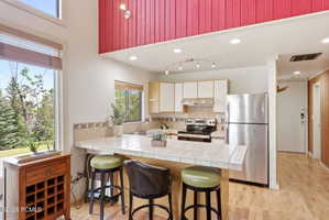 Kitchen area featuring a tile-top breakfast bar, white cabinetry, stainless steel appliances, and a wood-finish floor