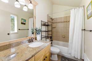 Full bathroom featuring a single vanity with a granite countertop, undermount sink, and wood-finish cabinetry