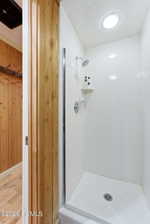 Shower enclosure with white subway tile walls, chrome fixtures, and an overhead light