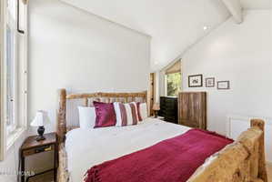 Vaulted ceiling with exposed beam, recessed lighting, and a large window providing natural light