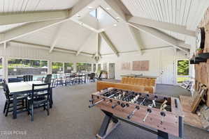 Spacious recreation area featuring a vaulted ceiling with exposed beams, skylight, and recessed lighting