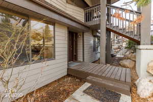 Exterior entrance featuring horizontal siding, a dark wood-finish entry door, and a wooden landing