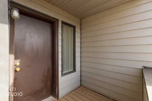 Entryway featuring a brown door with brass hardware, an exterior light fixture, horizontal siding, and a vertical window with obscured glass