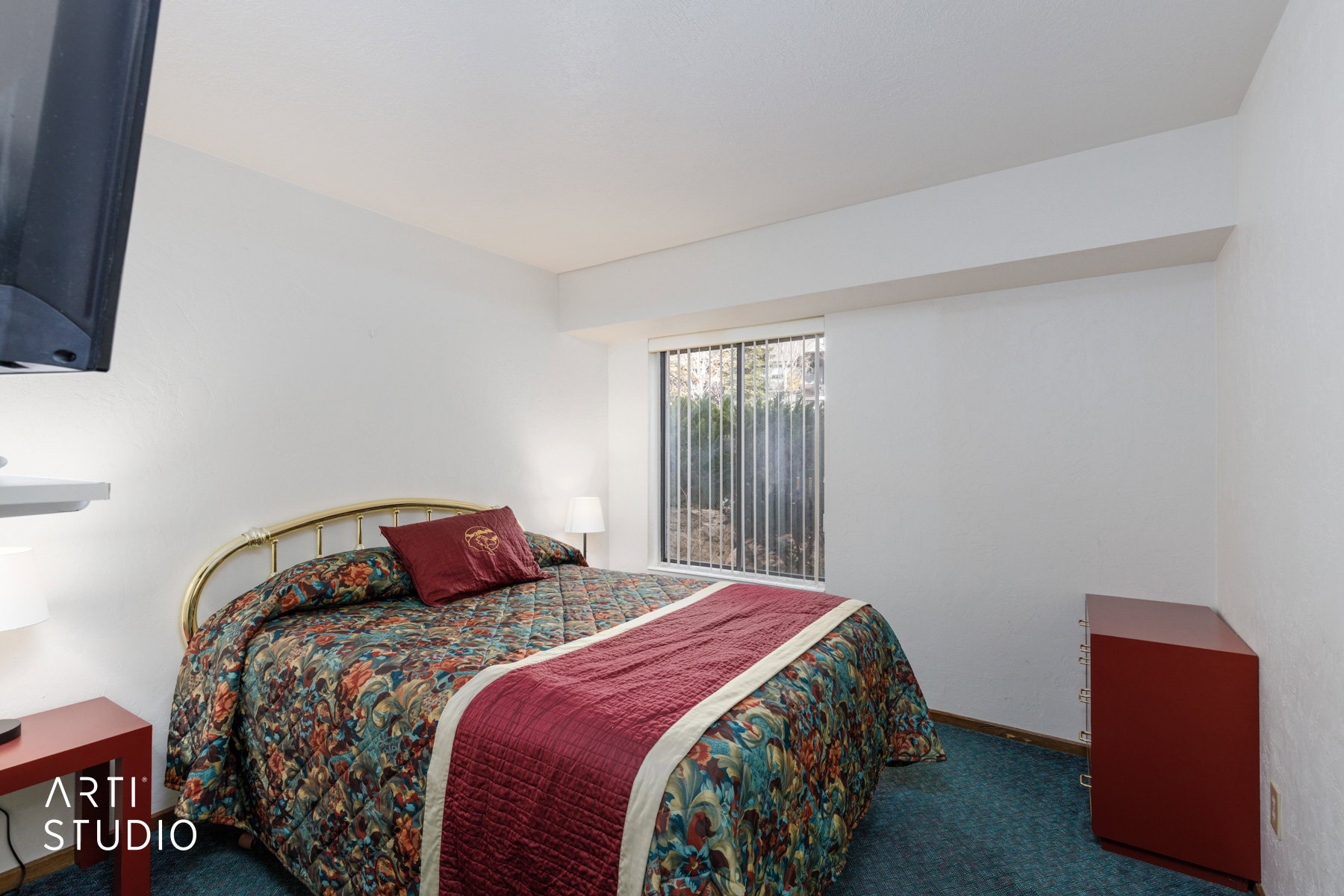 Bedroom featuring a window with vertical blinds, providing natural light