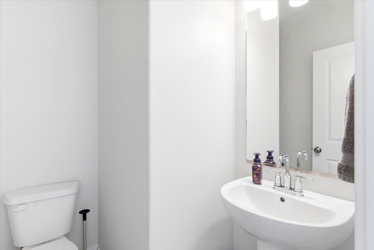 Pedestal sink with chrome faucet, illuminated by a two-light vanity fixture