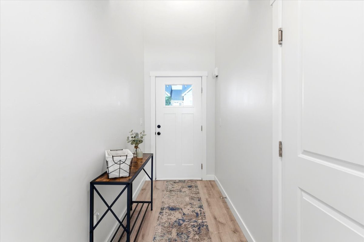 Entryway featuring wood-finish flooring, white paneled doors, and bright white walls