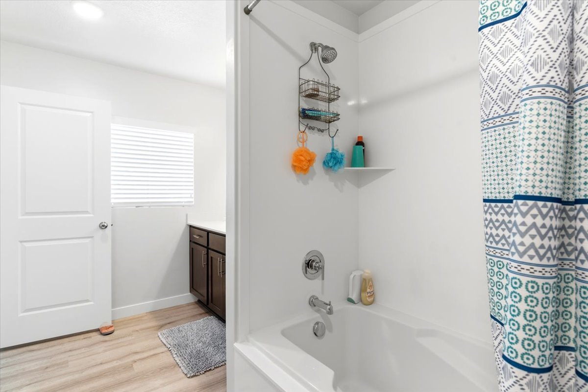 White bathtub with a chrome shower fixture and a built-in shelving unit