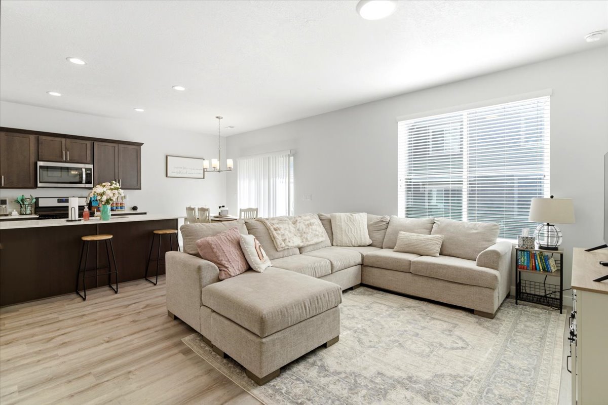 Bright living space featuring wood-finish flooring, recessed lighting, and a large window with blinds