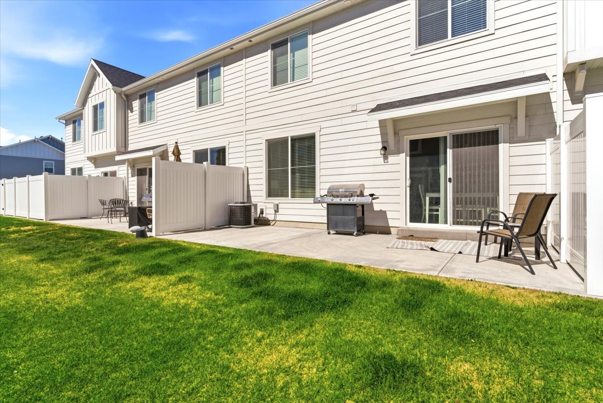 Rear exterior featuring a concrete patio, sliding glass door, and white vinyl privacy fencing