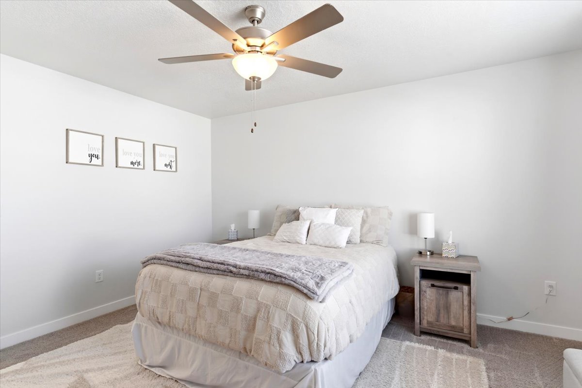 Carpeted room featuring a ceiling fan with light fixture, neutral wall paint, and baseboard trim