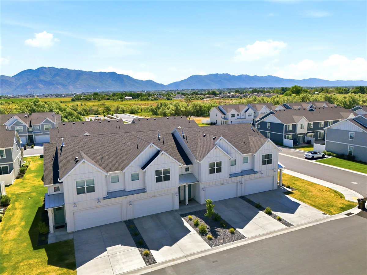 Modern townhomes featuring a white vertical siding exterior and dark shingle roofing