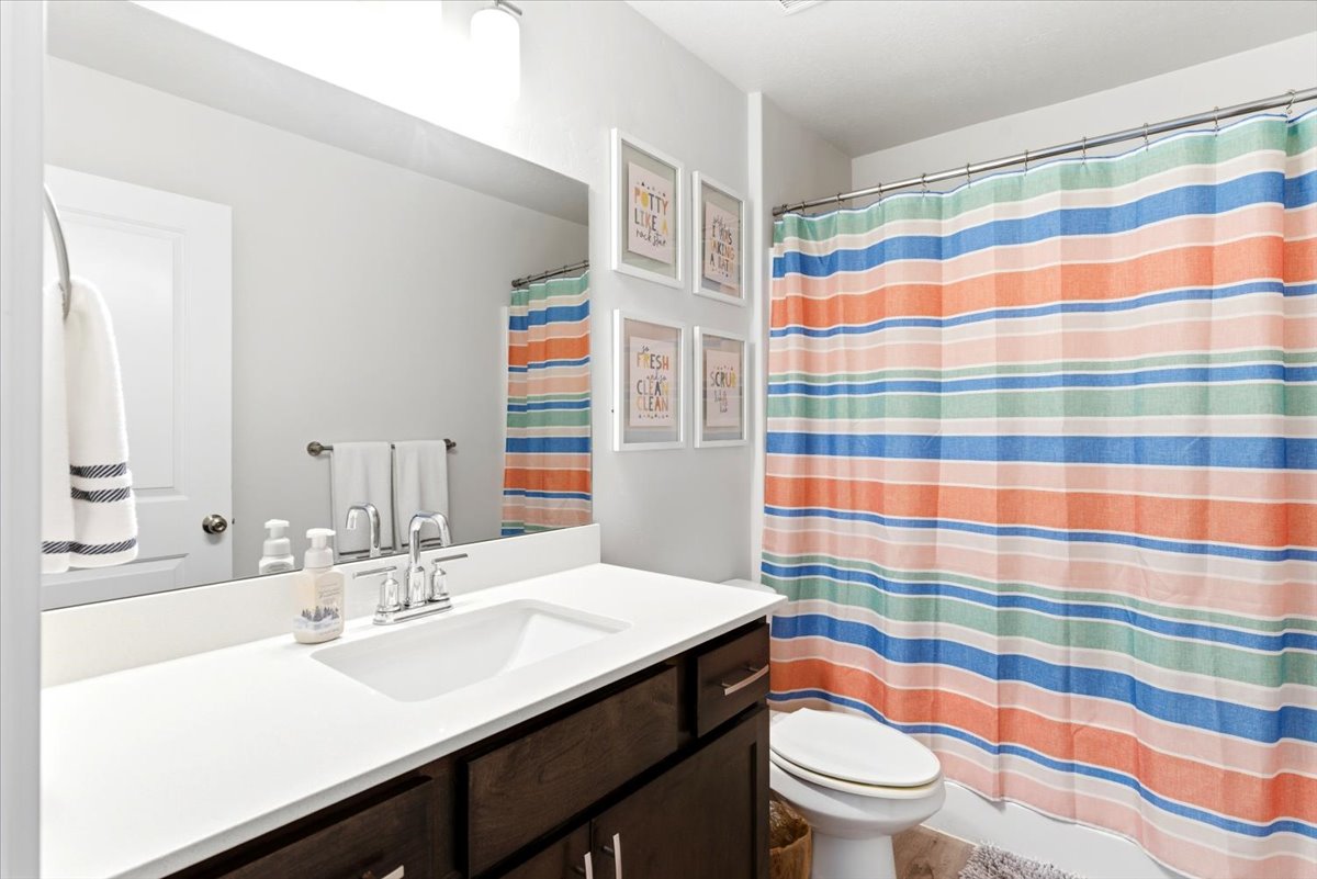 Bathroom featuring a built-in vanity with a white countertop and integrated sink, chrome faucet, and dark wood-finish cabinetry