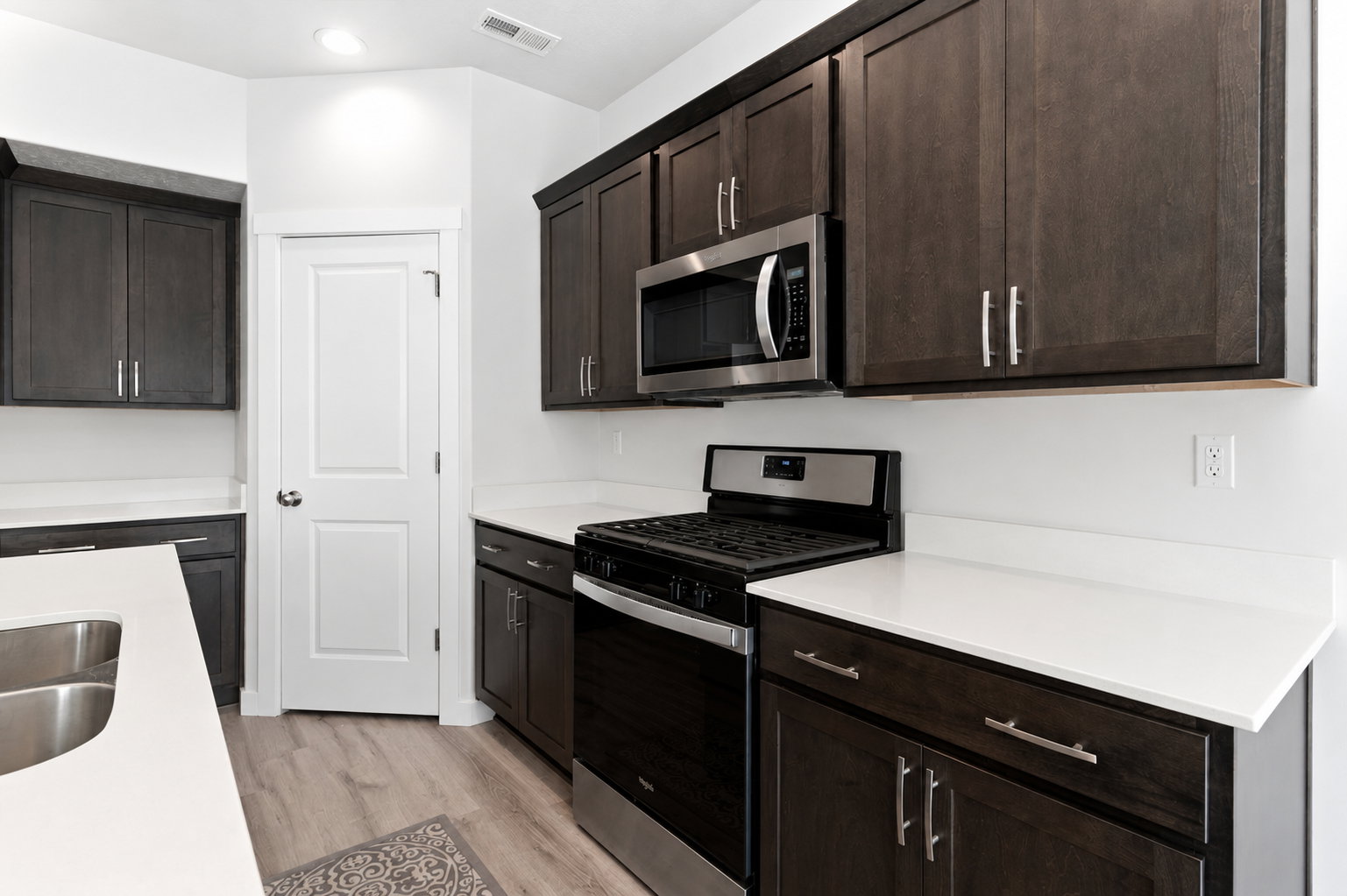 Modern kitchen featuring dark wood-finish cabinetry, stainless steel appliances, and light countertops