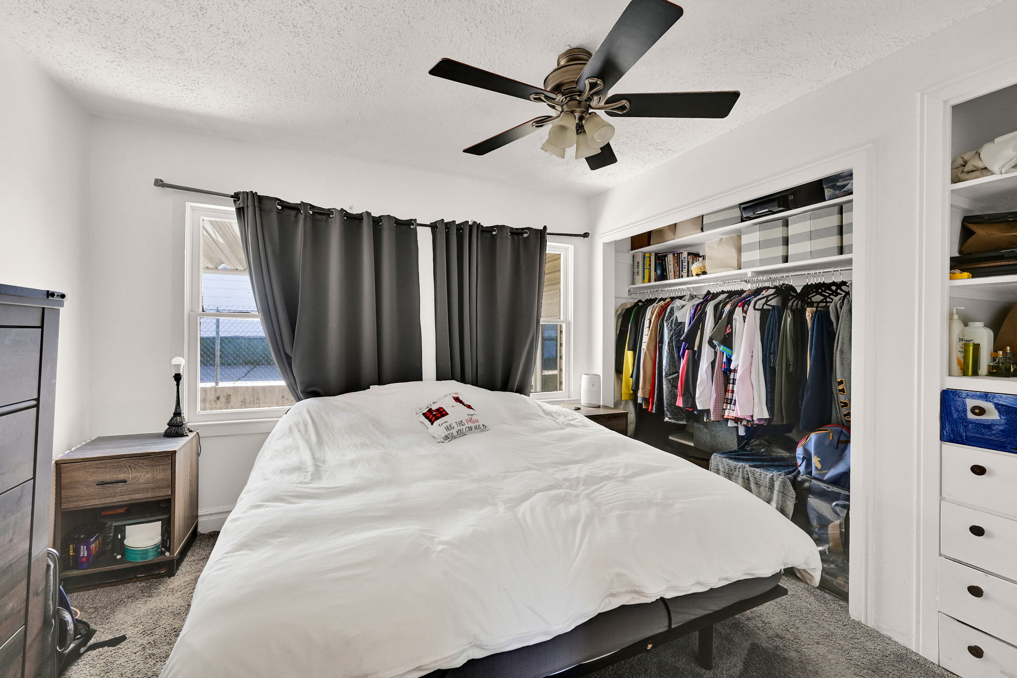 Bedroom featuring a ceiling fan with integrated lighting, two windows, and built-in closet shelving