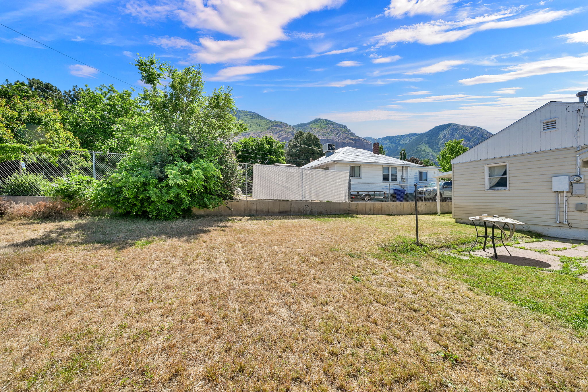Expansive outdoor space featuring a large lawn area and established perimeter fencing