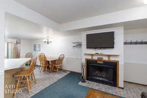 Living area featuring a black fireplace with a wood mantle, a white breakfast bar, recessed lighting, and a chandelier