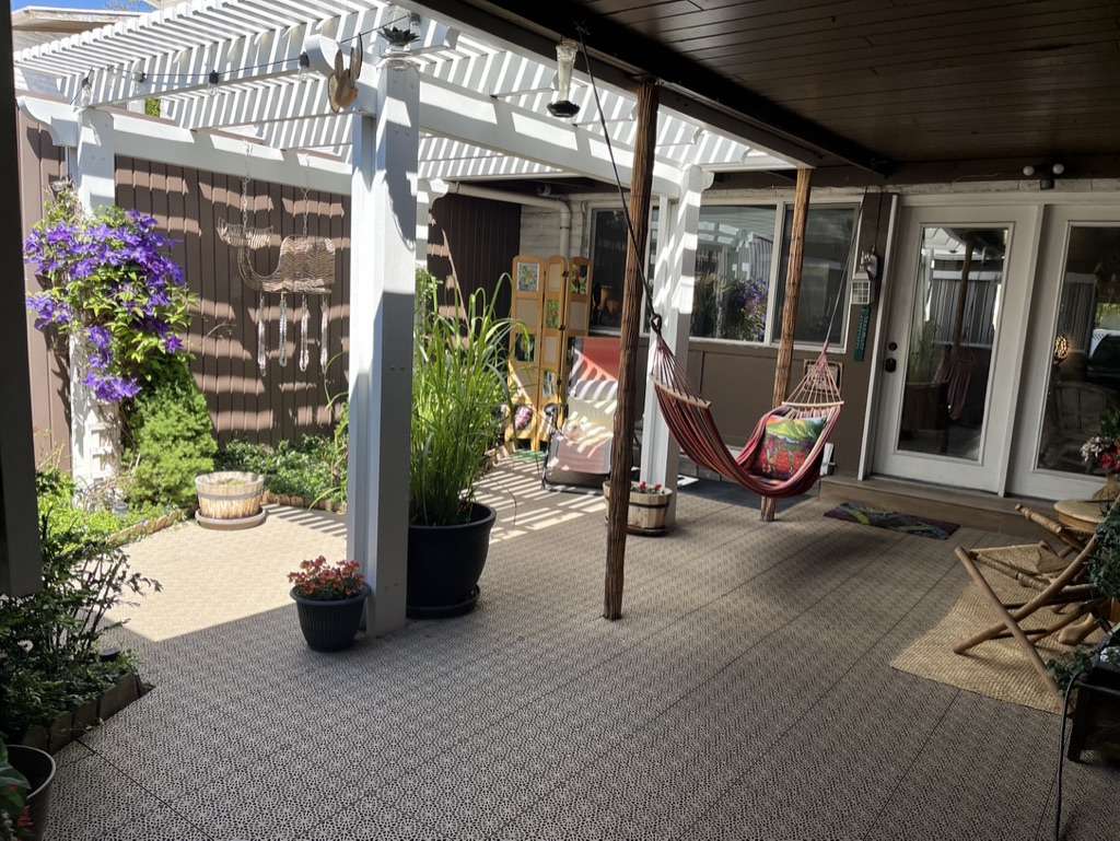 Outdoor patio area featuring a white slatted pergola and patterned tile flooring