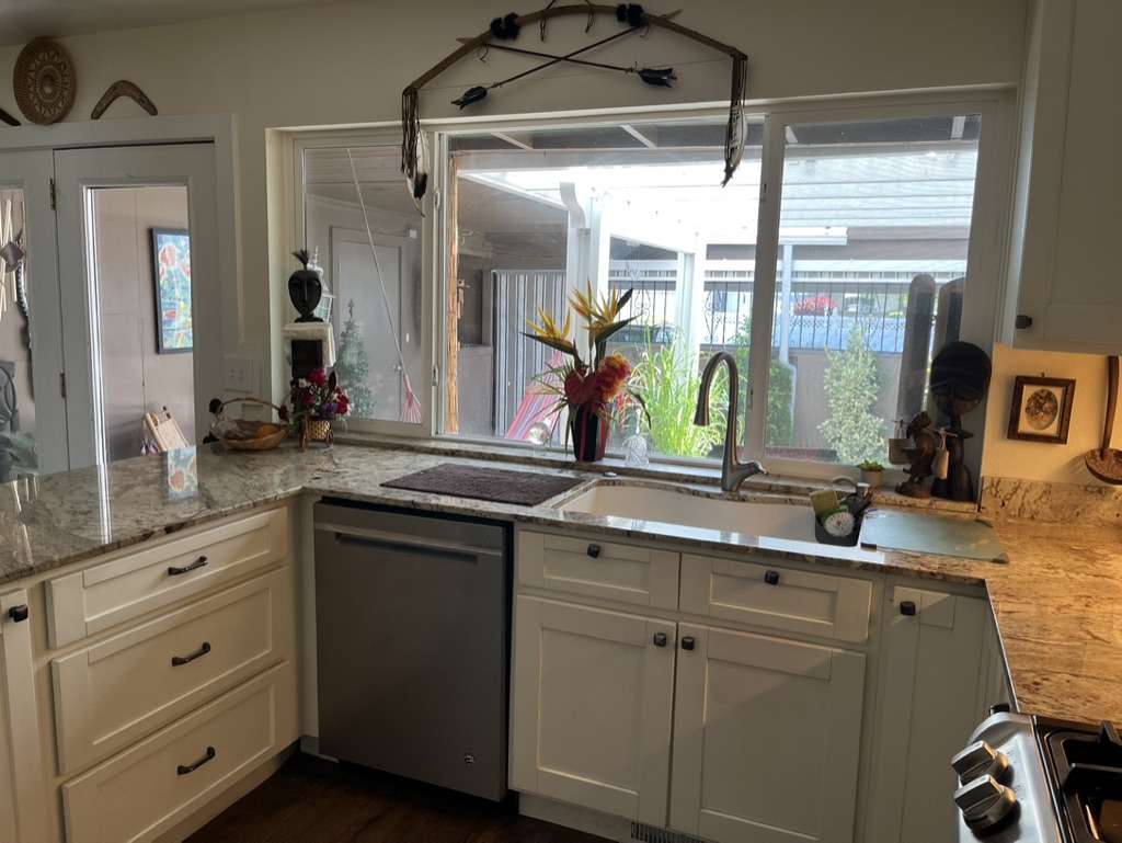 Kitchen workspace featuring granite countertops, white shaker-style cabinetry, stainless steel dishwasher, a single-basin sink with gooseneck faucet, and a large window