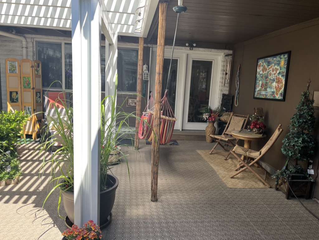 Shaded patio featuring a lattice pergola, textured outdoor flooring, and access to the interior via double glass doors