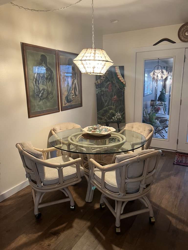 Dining area featuring dark wood-finish flooring, a glass-top table, and a glass-paneled door