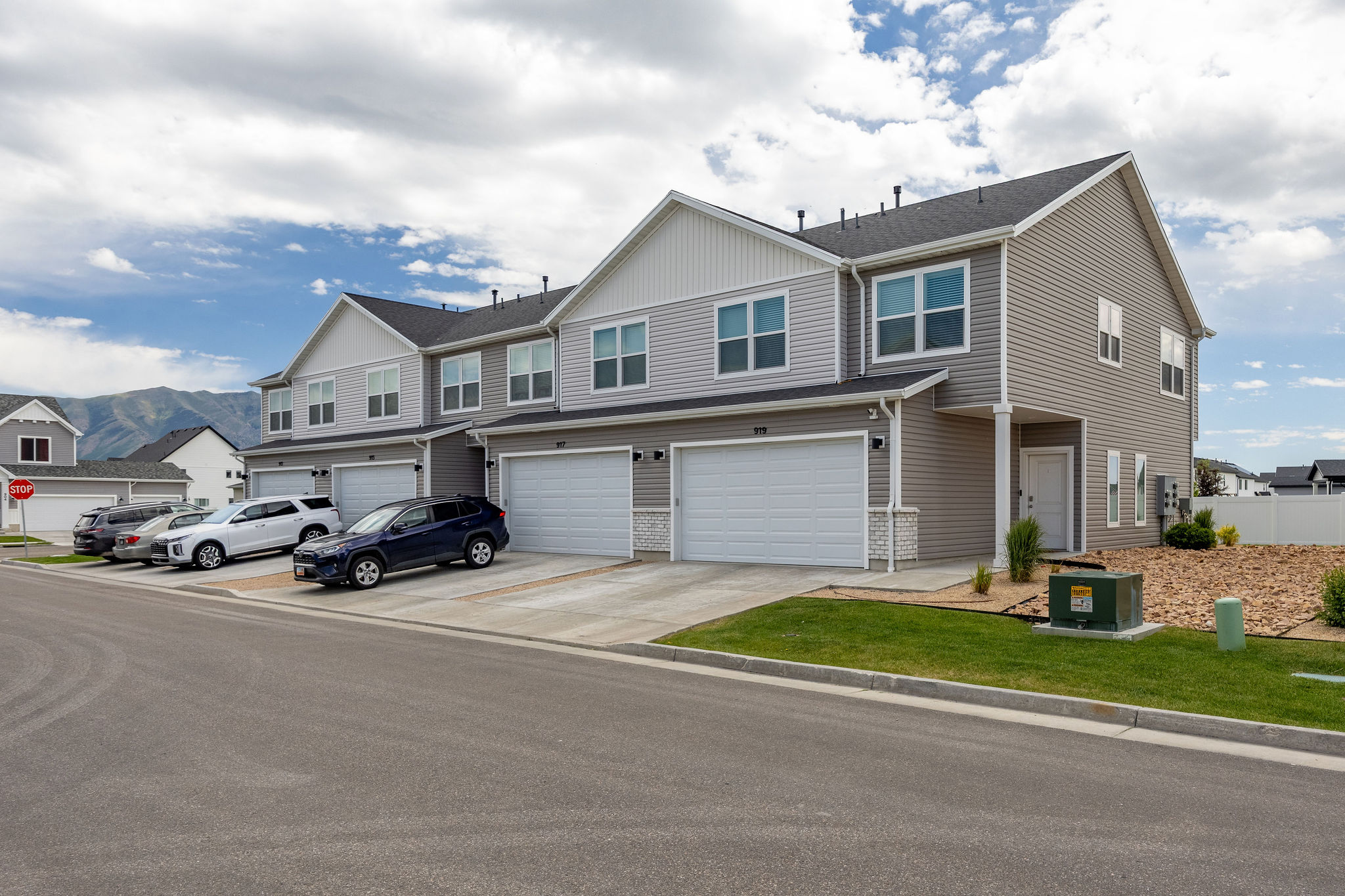 Modern townhome exterior featuring gray siding, white trim, a single-car garage, and a concrete driveway