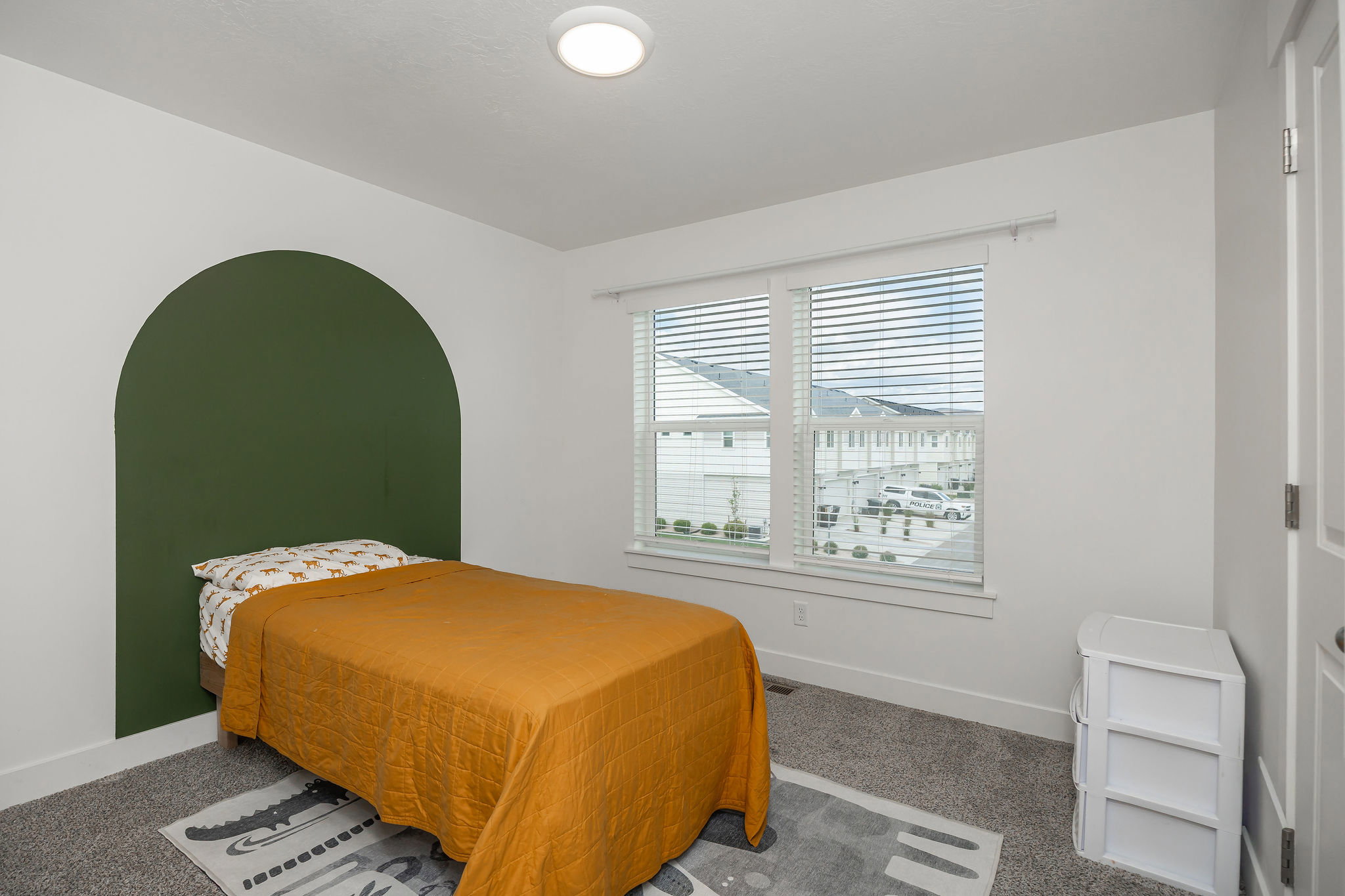 Bedroom featuring a decorative arched wall accent and a large window with blinds