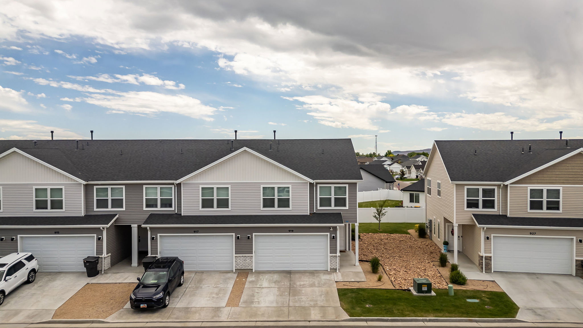 Modern townhome with attached garage, two-story design, dark shingle roof, and light-toned siding