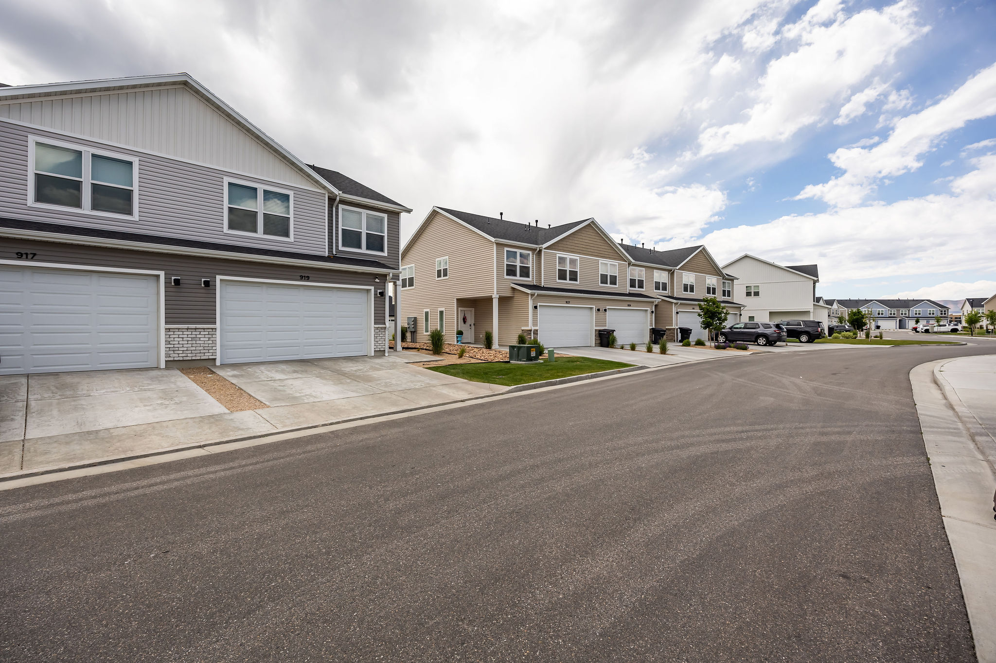 Modern townhome architecture featuring two-car garages, light gray siding, and white trim