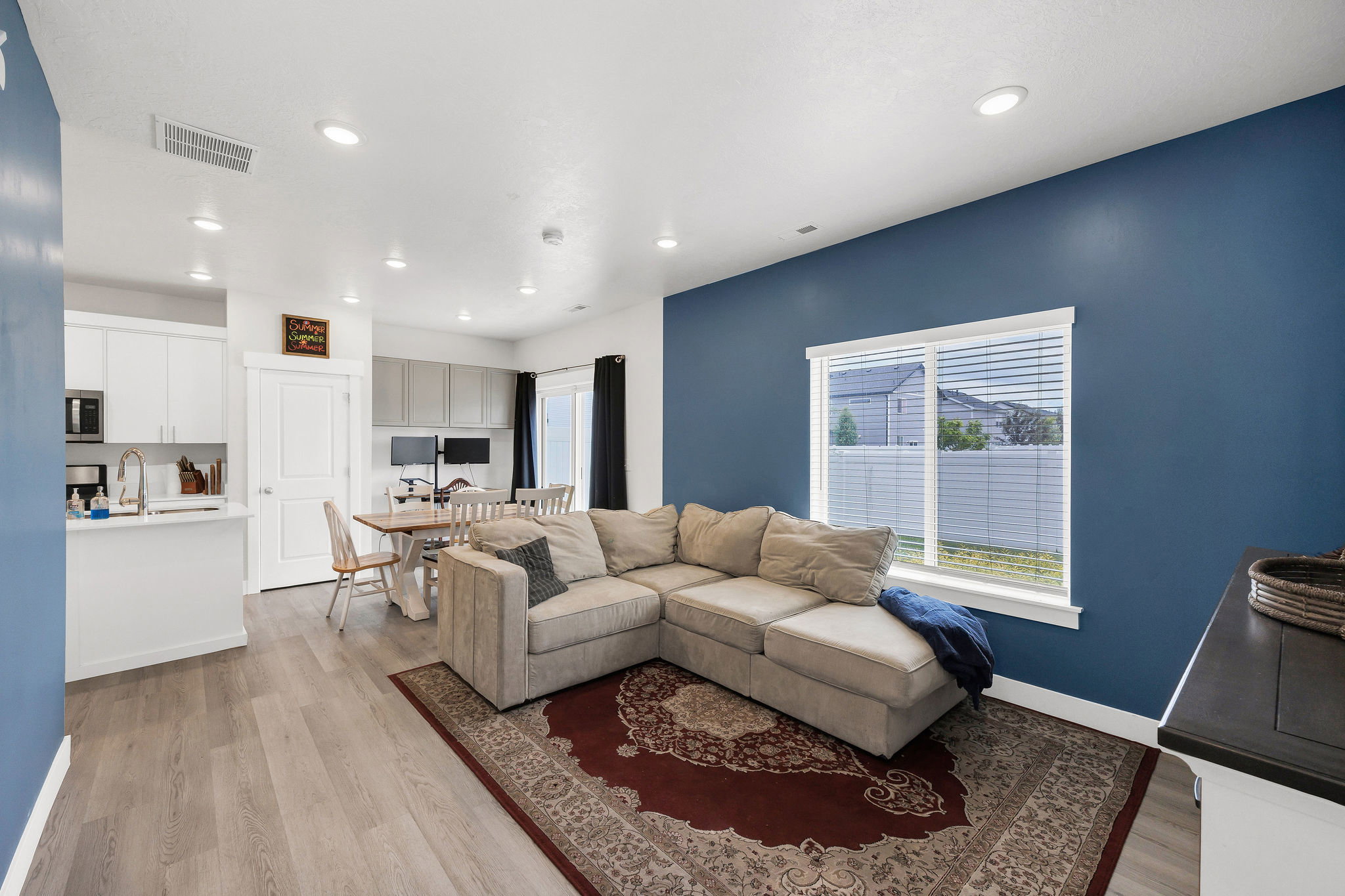Open-concept living space featuring wood-finish flooring, recessed lighting, and a window with blinds