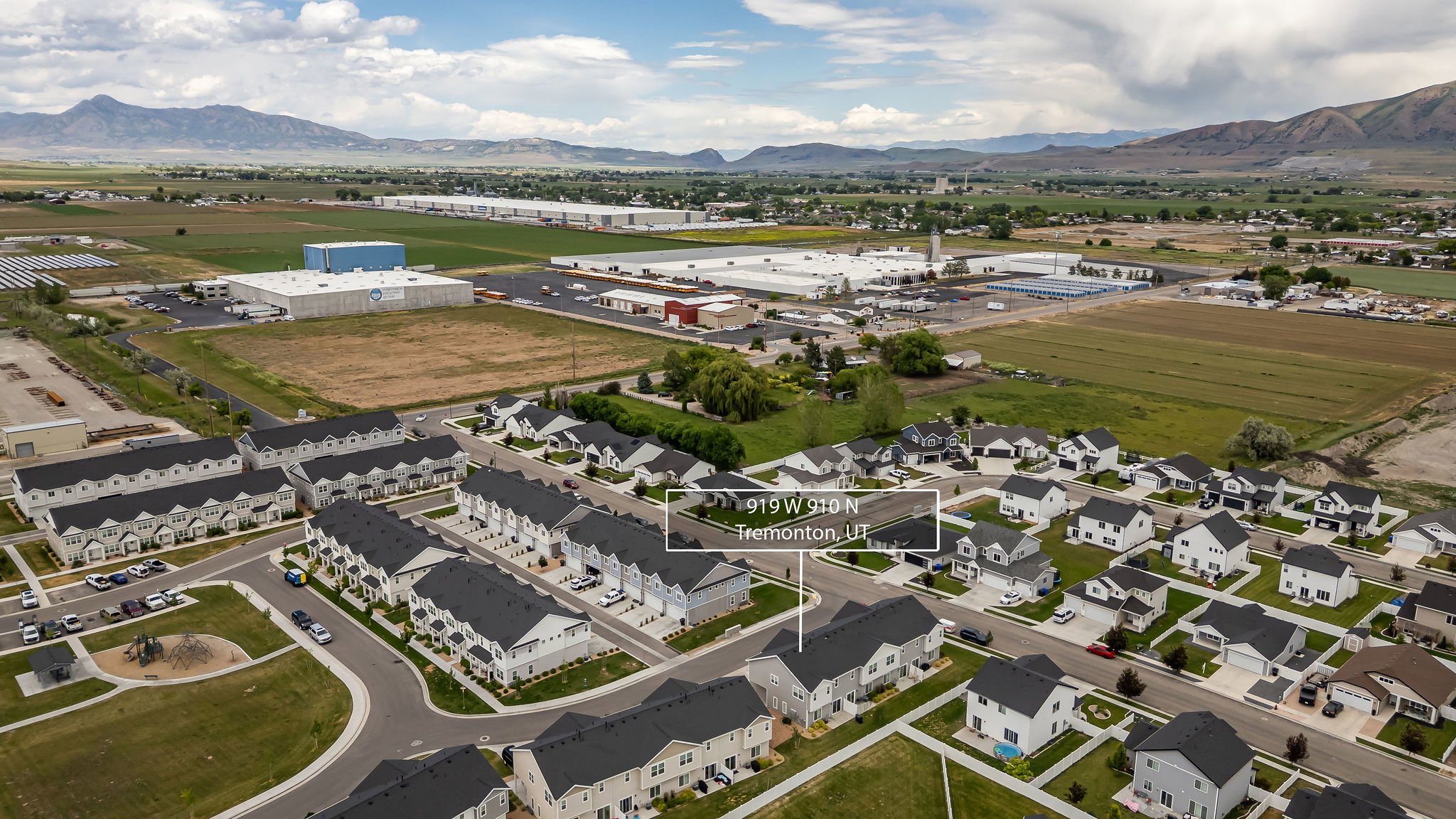 Aerial perspective showcasing a residential development with mountain backdrops and agricultural fields