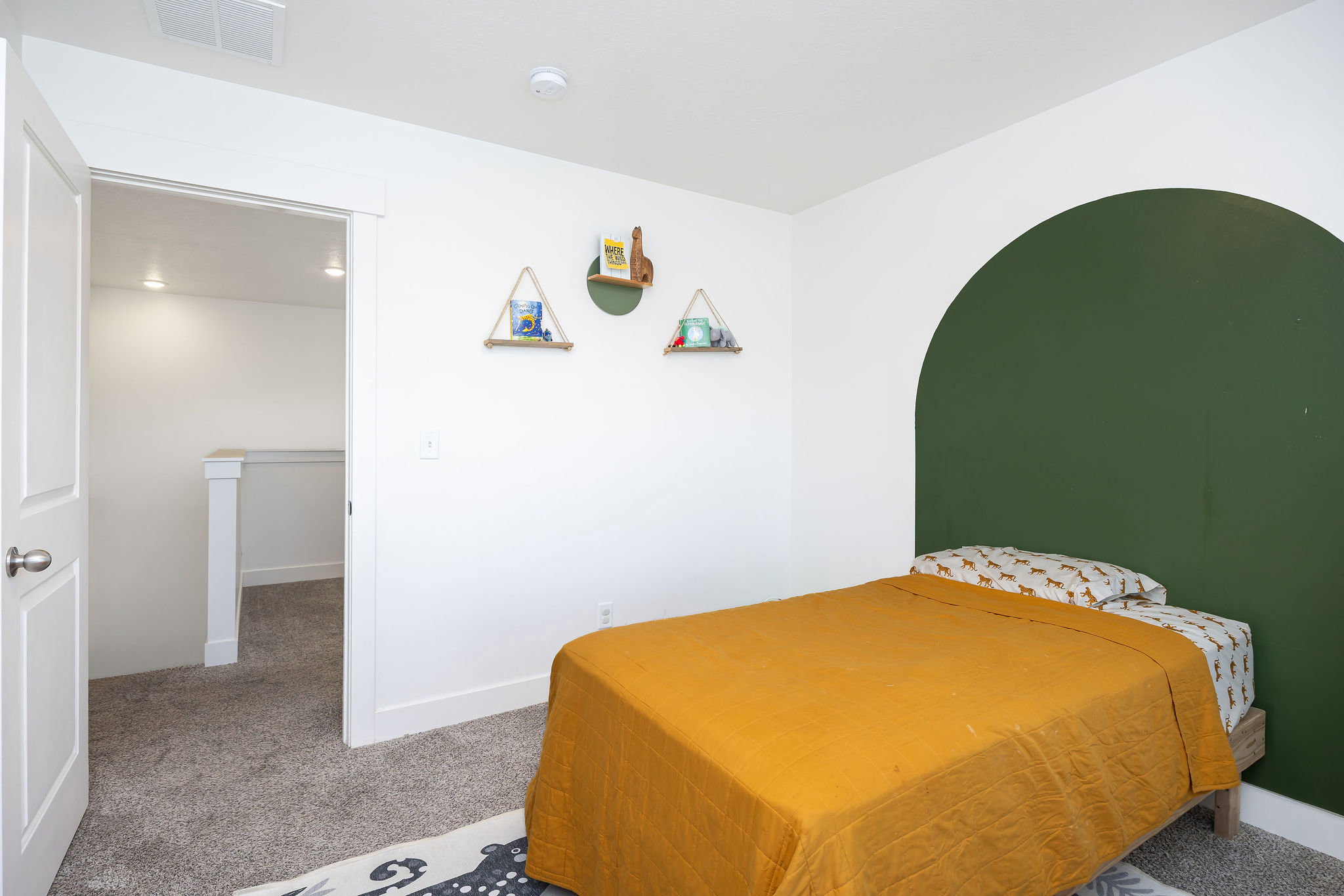 Bedroom featuring white walls and a distinctive green accent wall with an arched design