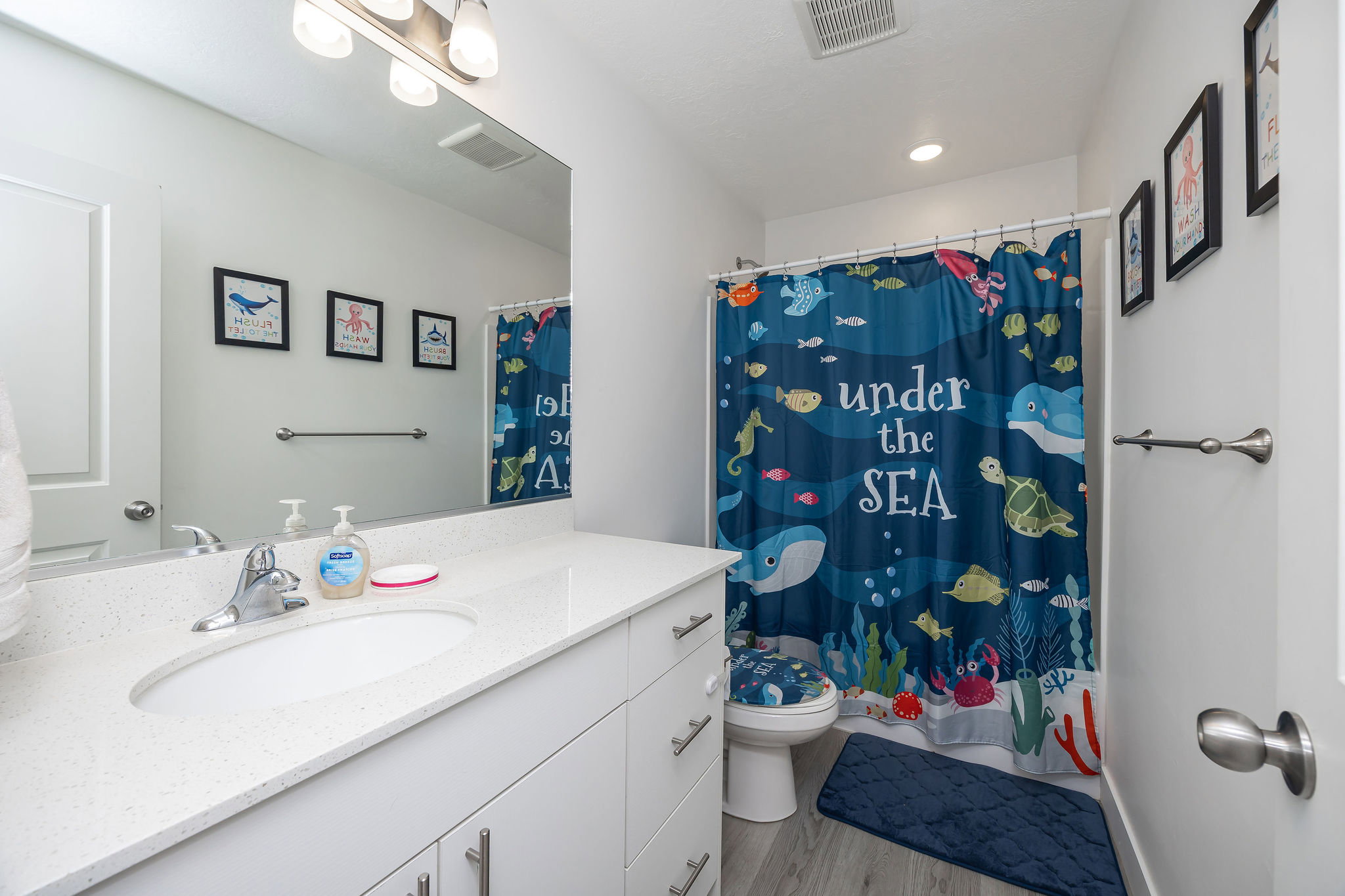 Bathroom featuring a white vanity with an integrated sink, polished chrome faucet, and a large mirror